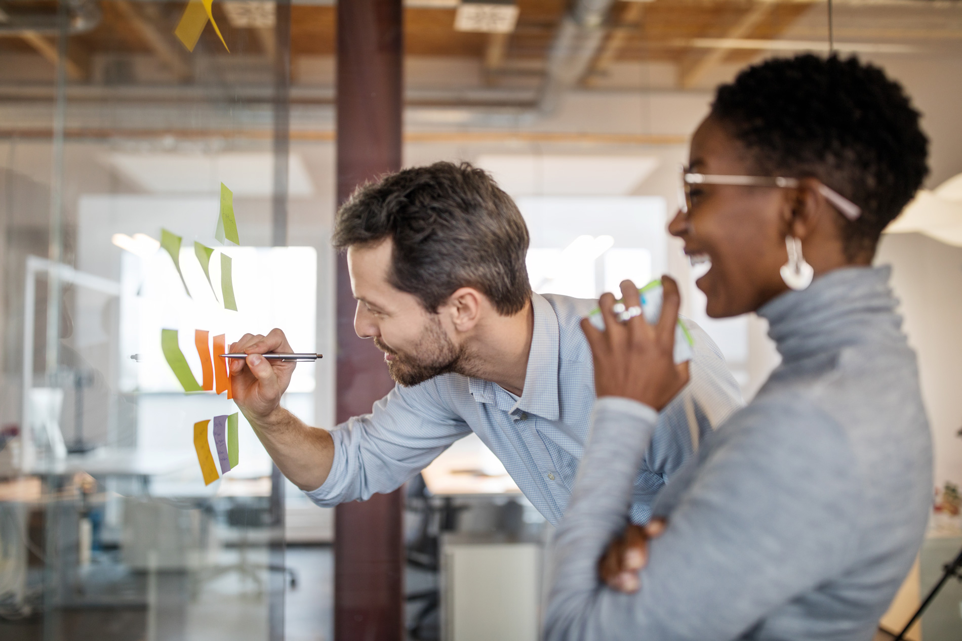 Man and woman next to a glass wall with post-it notes